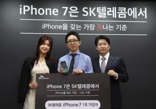 21일 서울 강남구 SKT 강남 직영점에서 아이폰7 1호 고객 박성기(가운데) 씨가 여행 상품권을 받고 가수 솔비(왼쪽), SK텔레콤 임봉호 본부장과 기념촬영을 하고 있다. 사진=연합뉴스